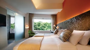 A hotel room with a large bed, a green chair, and a view of greenery outside. - D'Hotel Singapore managed by The Ascott Limited (Singapore)