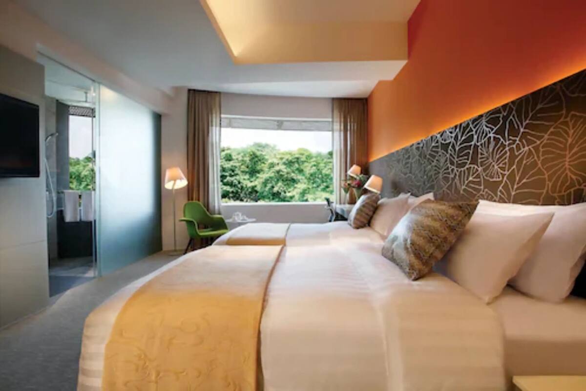 Una habitación de hotel con una cama grande, una silla verde y vistas a la vegetación.