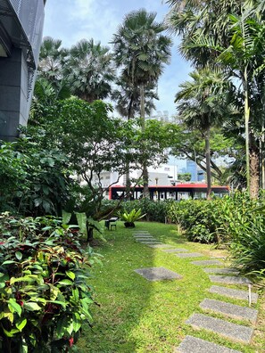 Stroll through the lush garden, surrounded by tropical plants and palm trees, along a winding stone pathway.