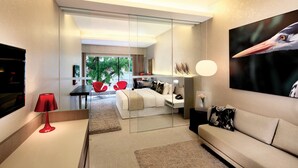 A modern living room with a sofa, a red lamp, a large painting, and a glass partition leading to a dining area with a table and chairs. - D'Hotel Singapore managed by The Ascott Limited (Singapore)