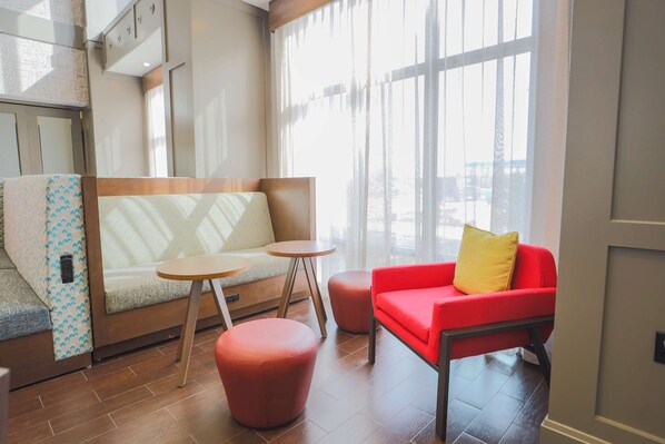 A modern interior with a sofa, ottoman, and red chair near large windows.