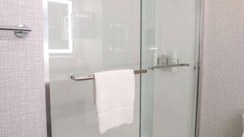 Une salle de bain moderne avec une douche à parois de verre, des toilettes blanches et un porte-serviettes.