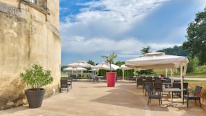 An outdoor patio with stone flooring, outdoor seating, and umbrellas. - Hotel Golf Chateau de Chailly (Chailly-sur-Armancon)