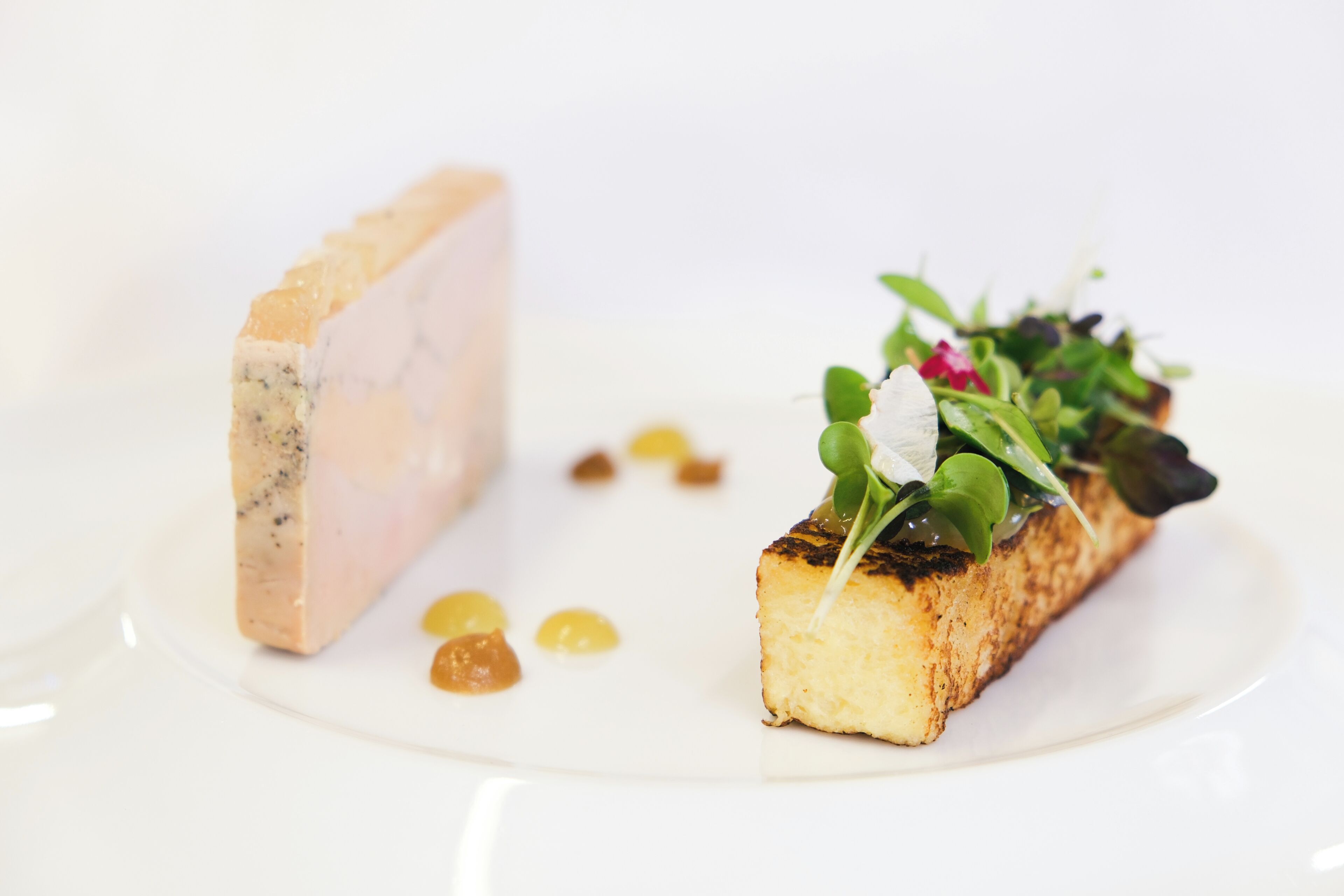Une assiette à dessert avec une part de gâteau et un morceau qui ressemble à un fromage à pâte molle ou à une préparation fromagère.