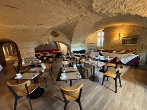 Un restaurante con paredes de piedra, mesas redondas y sillas.