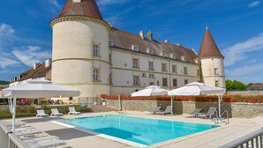 A large building with a swimming pool, sun loungers, and umbrellas. - Hotel Golf Chateau de Chailly (Chailly-sur-Armancon)