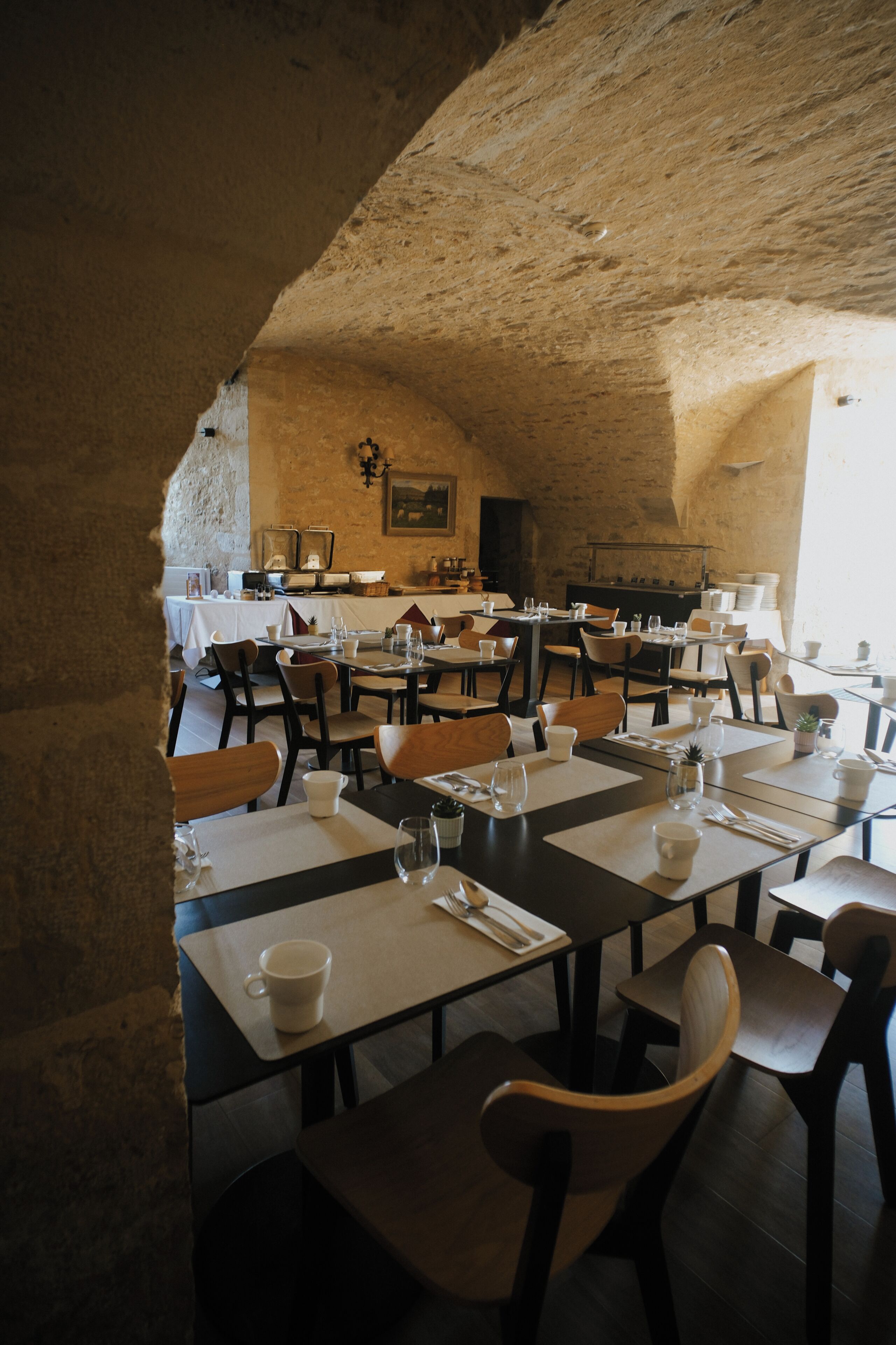 A rustic dining area with stone walls, wooden tables, and chairs.