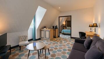 A modern hotel room with a loft bed, a desk, a sofa, and a television.