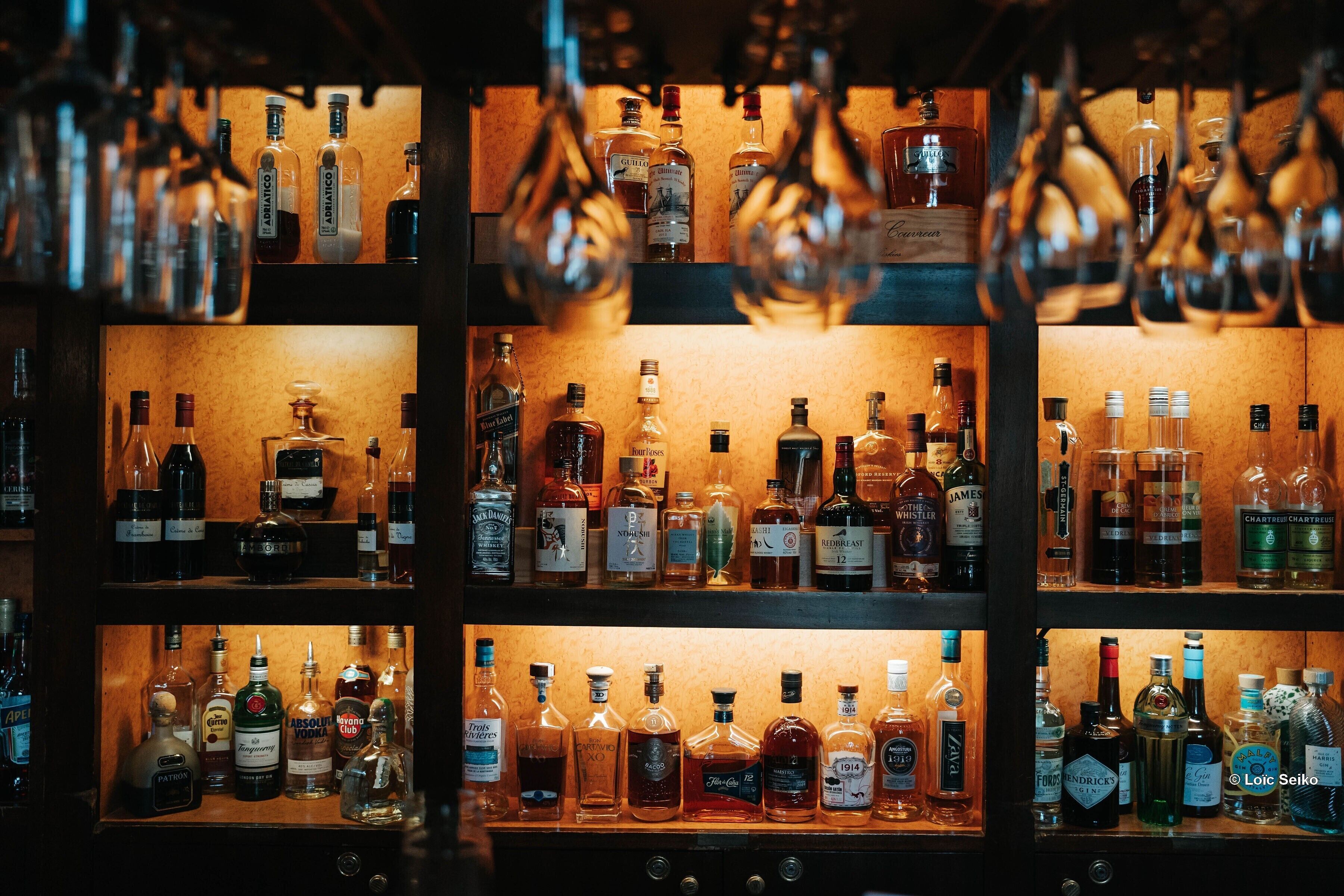 Un bar con varias estanterías llenas de botellas de licores.
