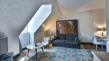Une chambre de style loft moderne avec un plafond en pente, une grande fenêtre, un canapé, une petite table, une chaise et un tableau.