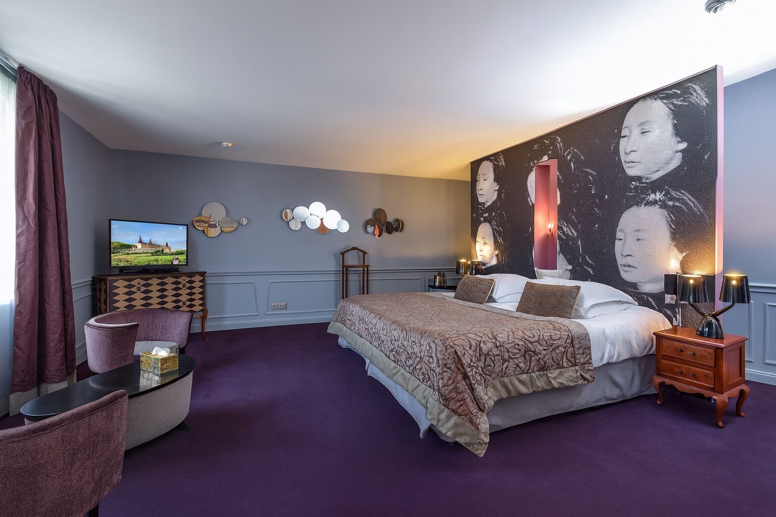A bedroom with a large bed, a television, a desk, and a chair.