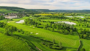 A golf course with bunkers, water hazards, and a large building in the background. - Hotel Golf Chateau de Chailly (Chailly-sur-Armancon)