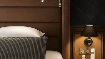 A hotel room with a bed, a bedside table with a lamp, a phone, and a bottle of water.