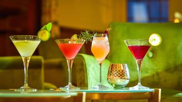 Vier Cocktails auf einem Tisch, im Hintergrund eine grüne Couch.