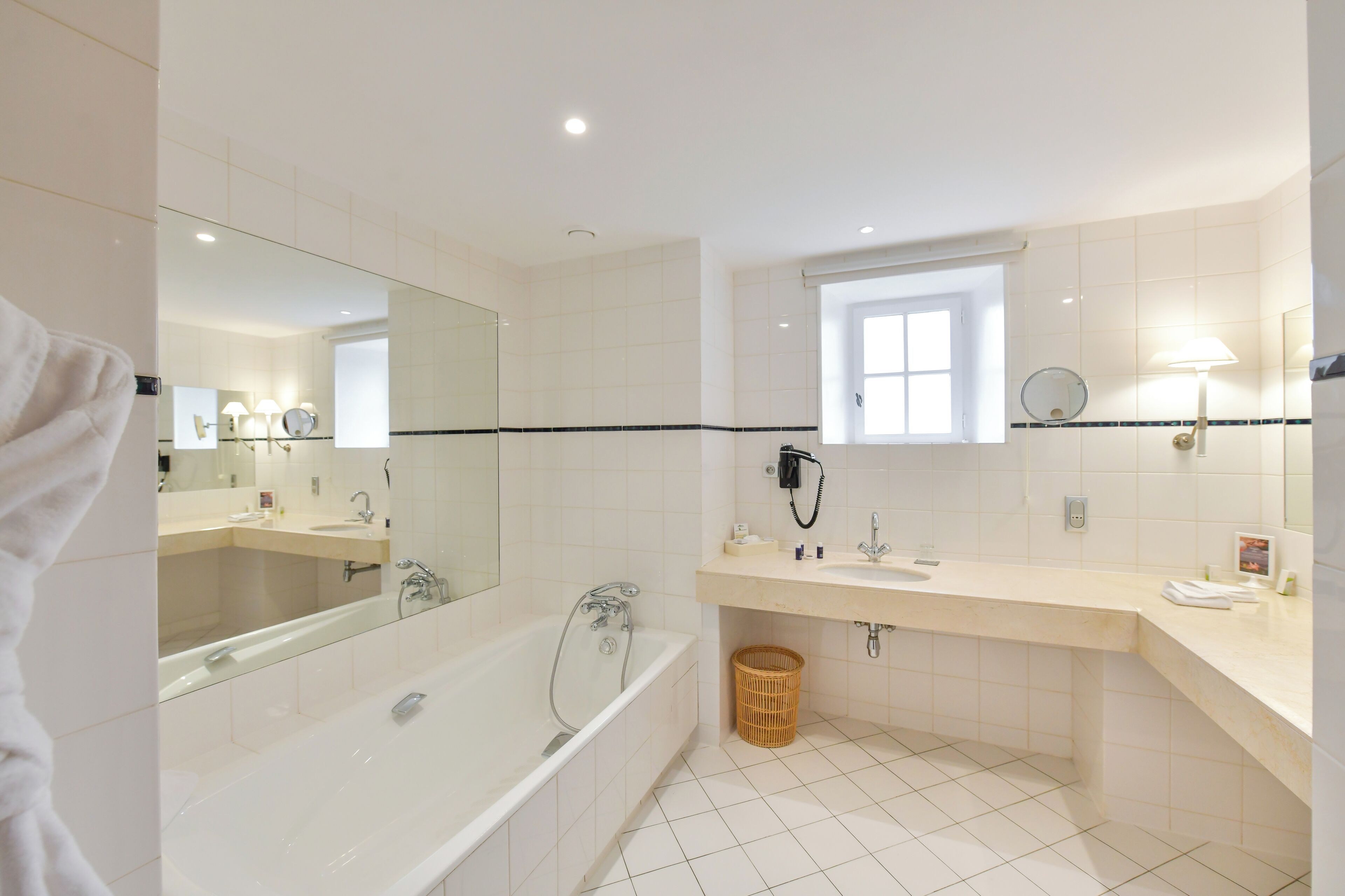 Un baño moderno con bañera, lavamanos, espejo y ventana.