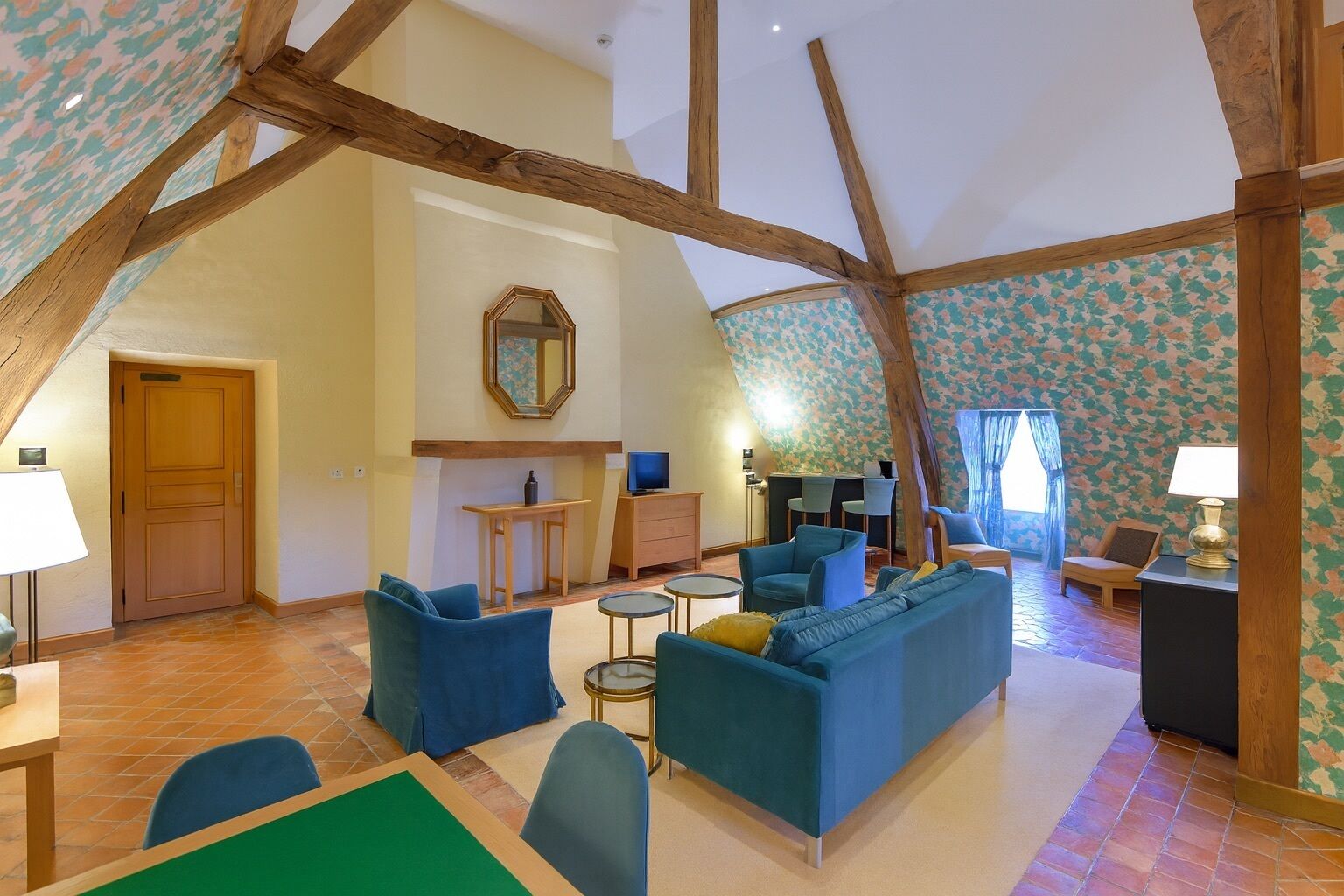 Amplia sala de estar con techo alto, vigas de madera a la vista, chimenea y un conjunto de sofás y sillones.