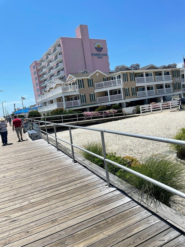 A wooden boardwalk leading to a beach with a hotel in the background.