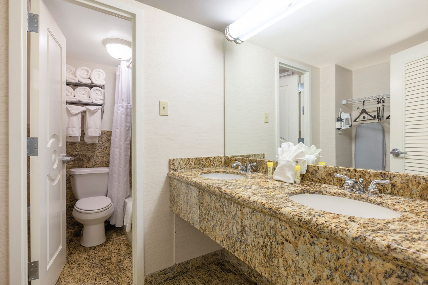 A bathroom with two sinks, a toilet, and a shower area.