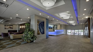 A spacious lobby with a reception desk, seating area, and a large plant. - Port-O-Call Hotel (Ocean City)