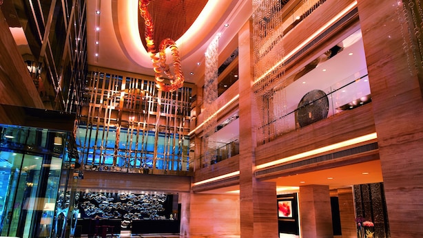 Un vestíbulo amplio con techo alto, iluminación moderna y un elemento decorativo central.
