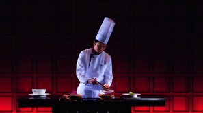 A chef in a white uniform with a tall hat, preparing food on a stove. - Tangla Hotel Beijing (Beijing)