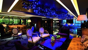 Un área de lounge moderna con barra, asientos e iluminación azul en el techo.