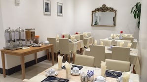 A dining area with tables set for service, a buffet station, and a mirror on the wall. - The Firs Lodge (Hounslow)