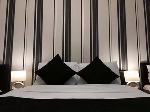 A hotel room with a bed, two black pillows, and two bedside lamps.
