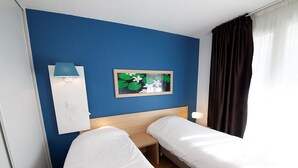 A hotel room with two single beds, a nightstand, a framed picture, a lamp, and a window with curtains. - Residhome Clermont Ferrand Gergovia (Clermont-Ferrand)