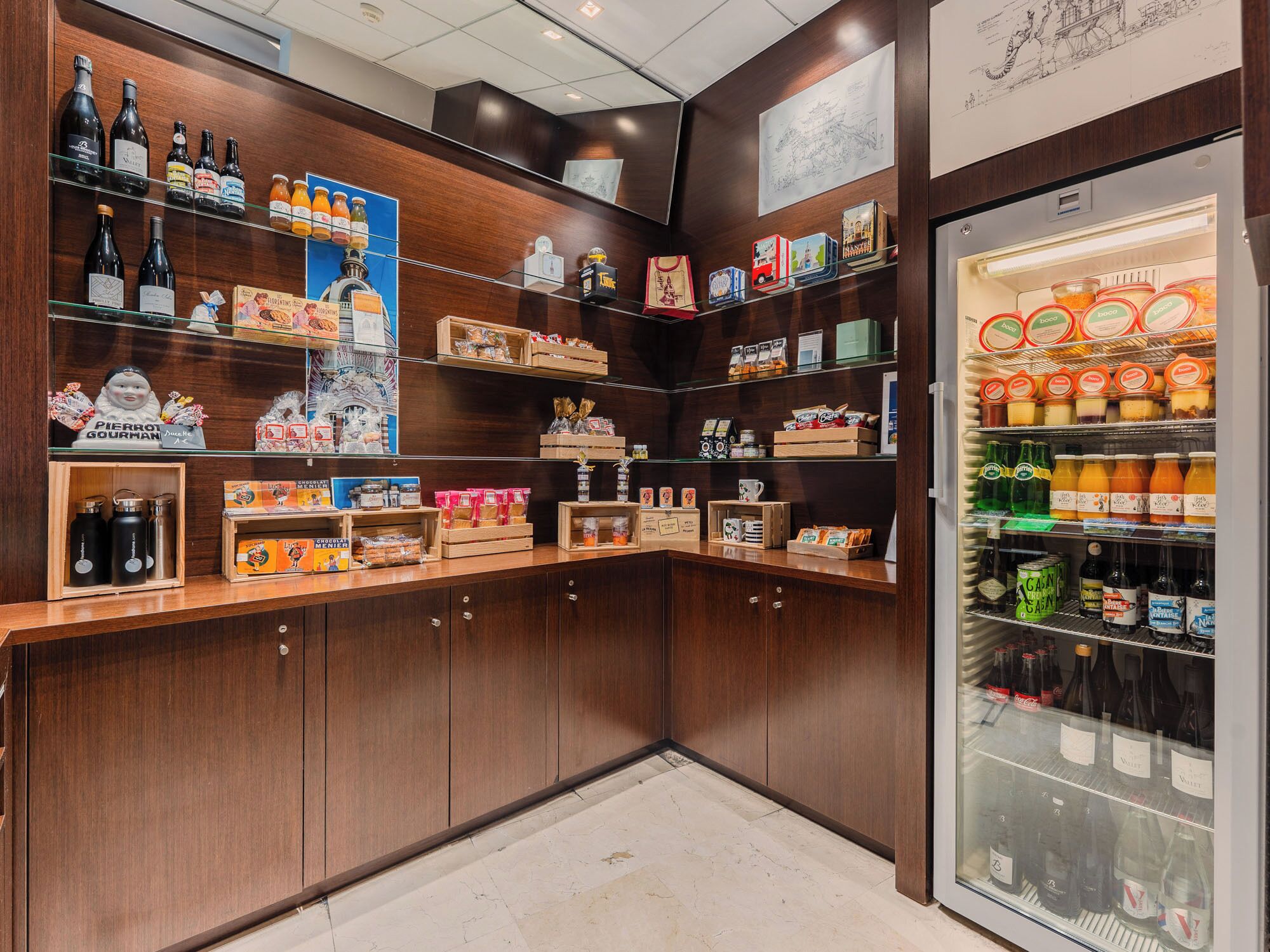 Zona de bar bien surtida con estantes de bebidas, aperitivos y un expositor refrigerado.