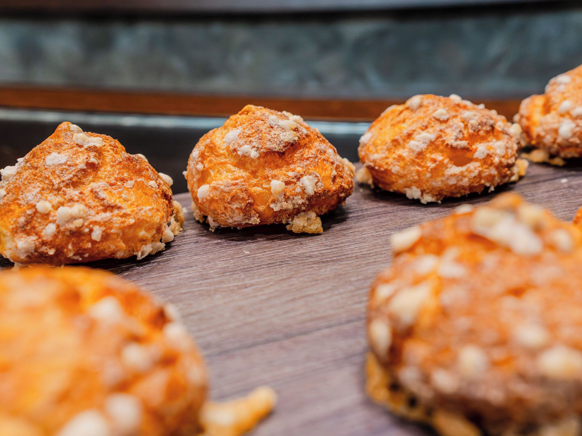 A close-up of round pastries with a crumbly topping, placed on a wooden surface.