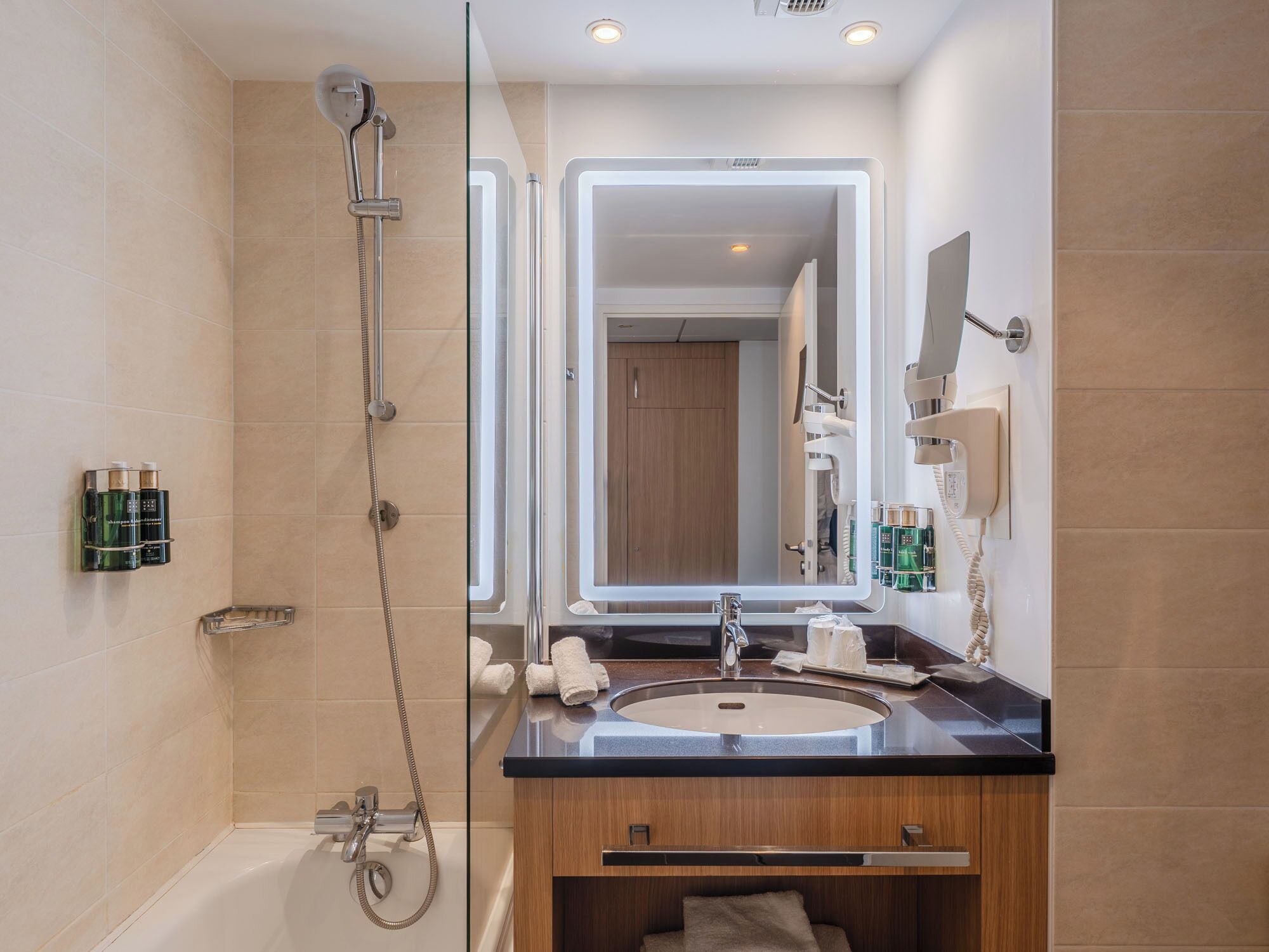 A modern bathroom with a glass-enclosed shower, a vanity with a sink, and a large mirror.