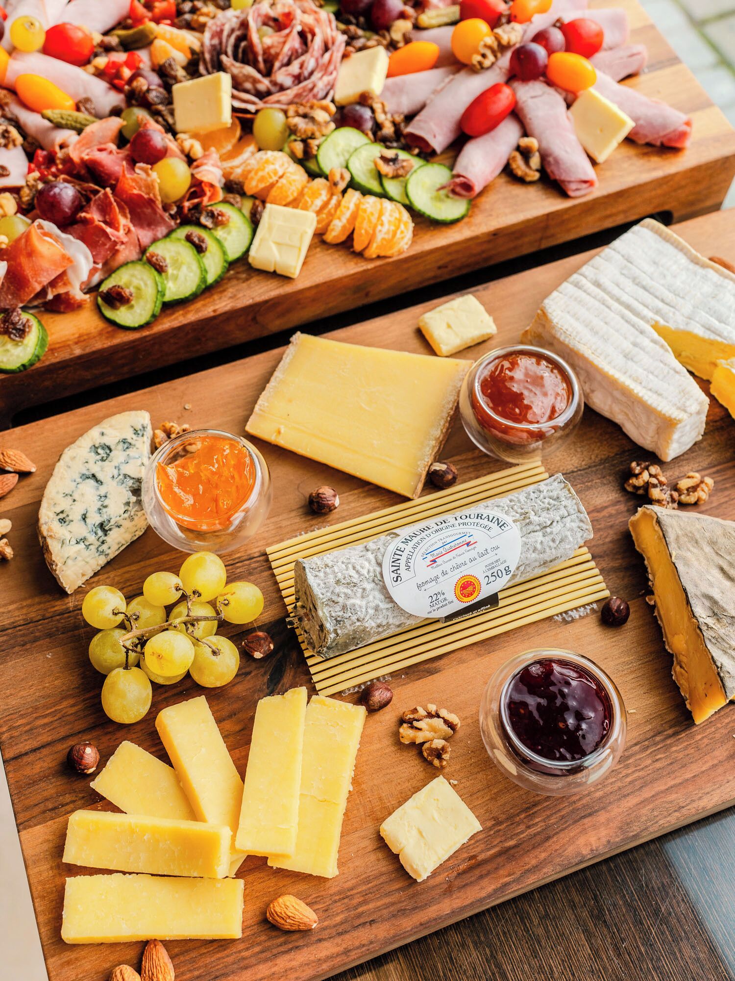 Une variété de fromages, de noix et de fruits présentés sur des planches en bois.