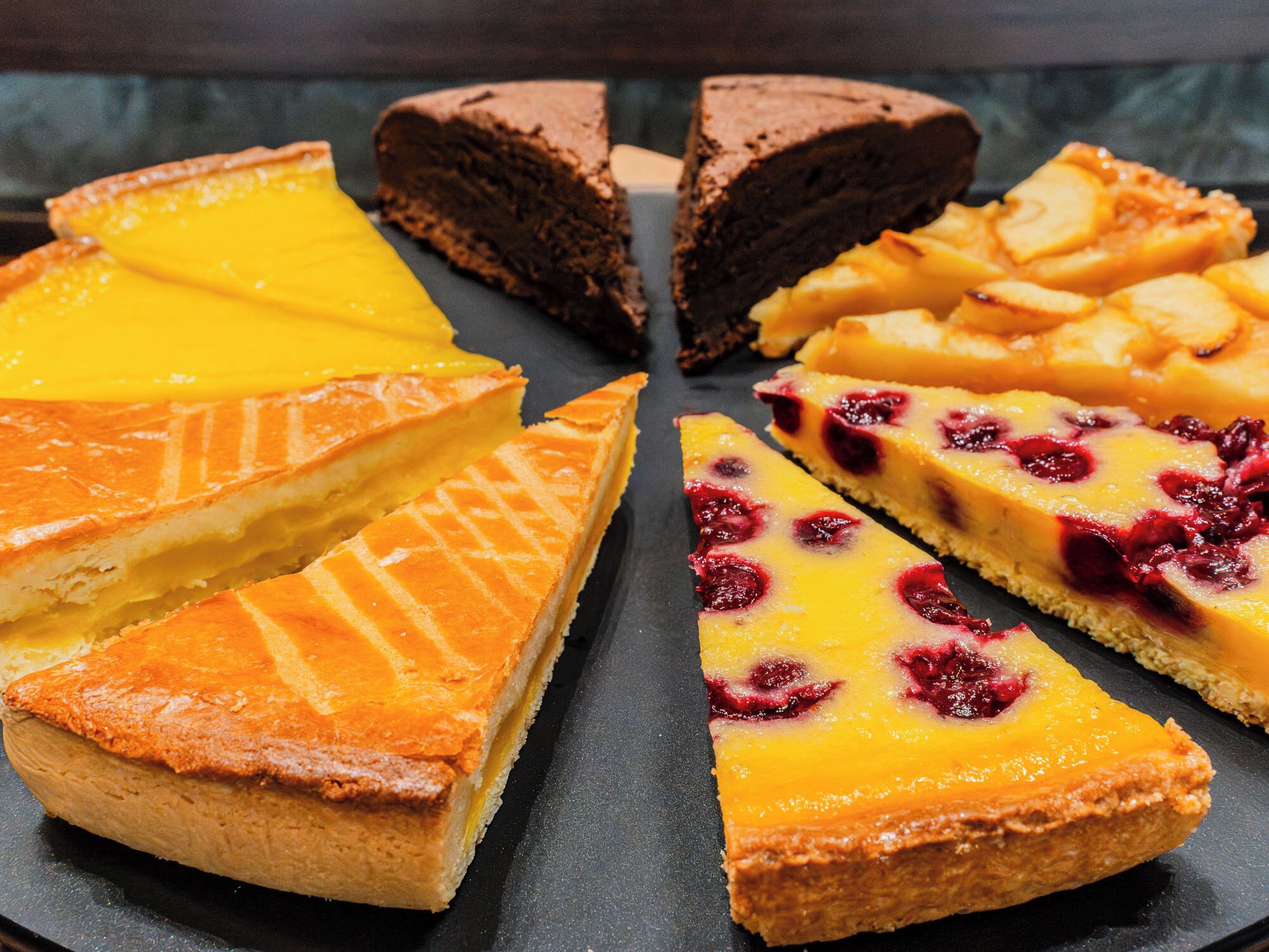 Diversas tortas sobre um prato de ardósia escura.