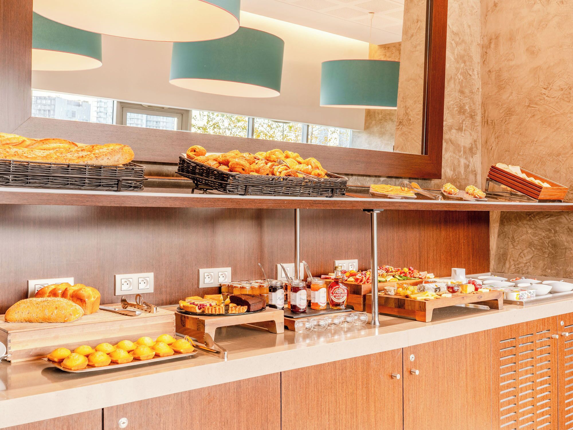 A buffet with various breads, pastries, and fruits.
