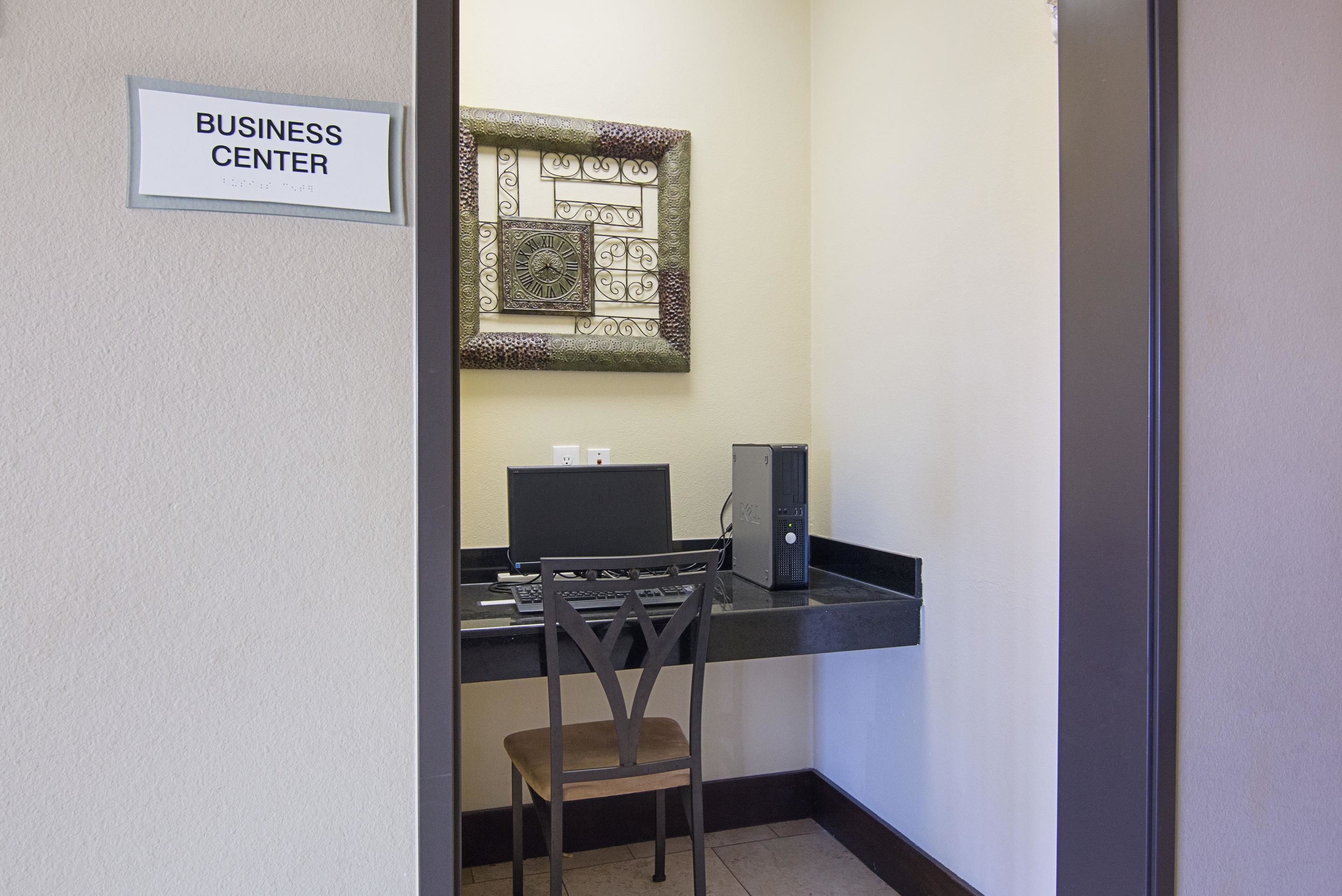 A business center with a computer desk, a chair, and a wall-mounted clock.