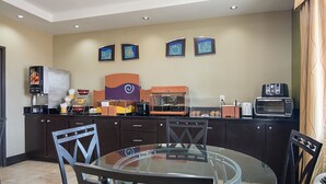 Una cocina moderna con mesa de comedor de vidrio, armarios oscuros y varios electrodomésticos, incluyendo un microondas y un tostador.