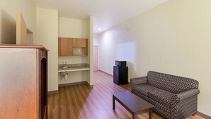 Um espaço de estar compacto com cozinha compacta, sofá estampado e uma mesa pequena.