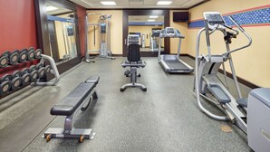A gym with treadmills, a bench, dumbbells, and a weight machine.