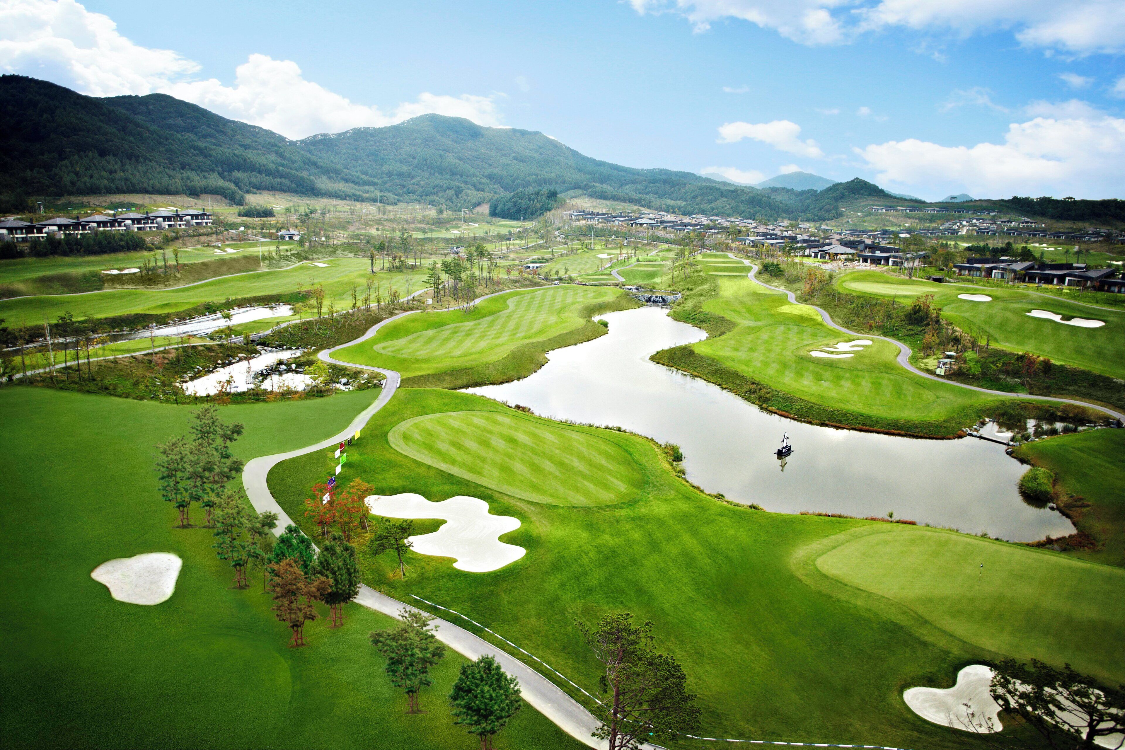 A golf course with multiple bunkers, water hazards, and a pond.
