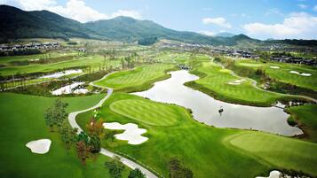 A golf course with multiple bunkers, water hazards, and a pond.