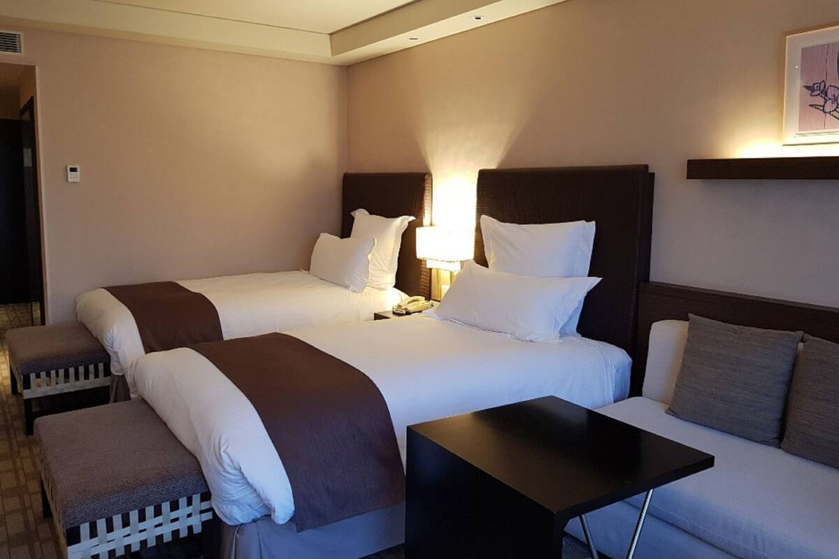 Una habitación de hotel con dos camas, una mesita y un sofá.