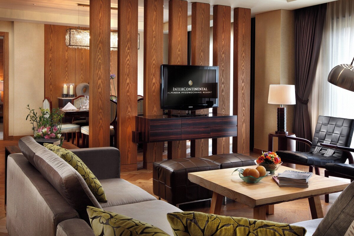 A modern living room with a sofa, a coffee table, and a television in the background.