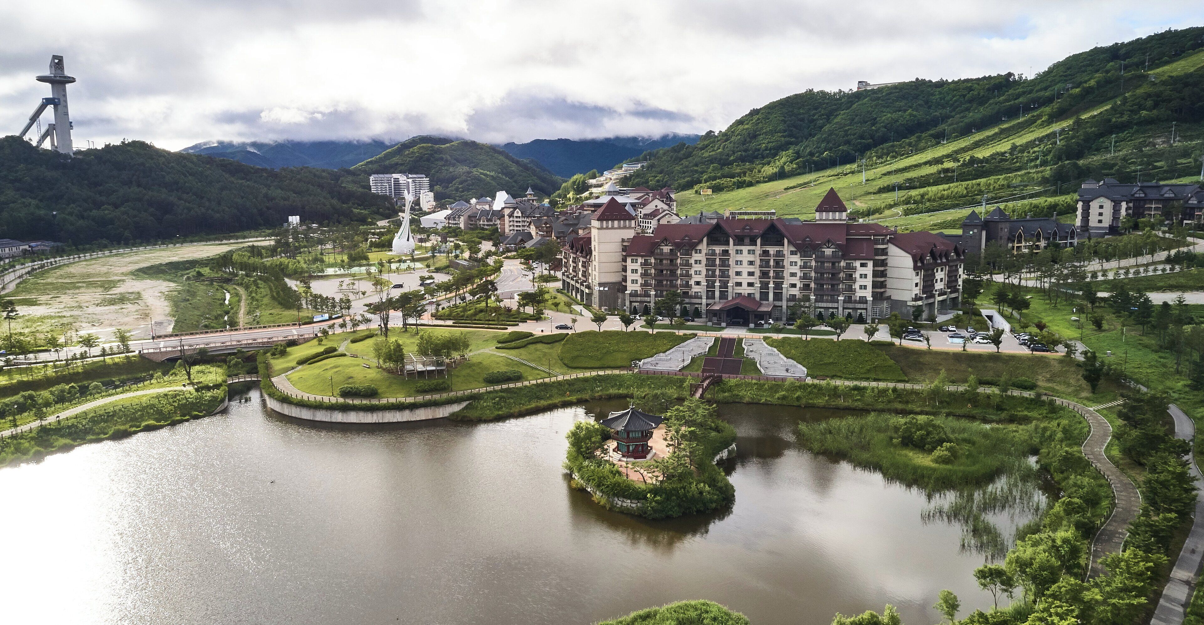 Ein Hotel mit Innenhof, einem See und einer Brücke.