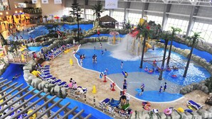An indoor water park with multiple pools, slides, and water play areas.