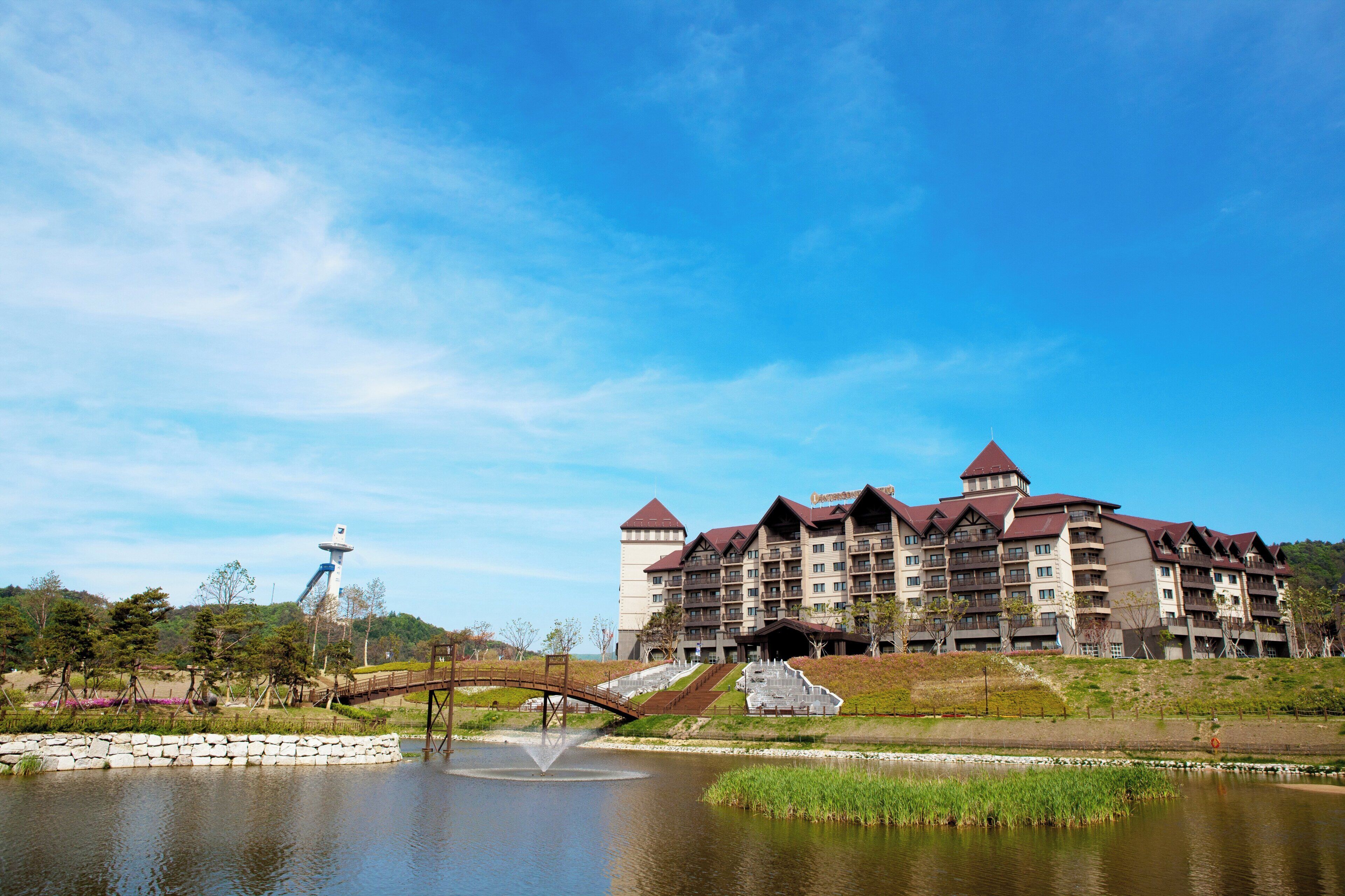A hotel with multiple floors, a central courtyard, and a body of water.