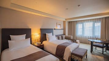 A hotel room with two beds, a desk, and a chair.