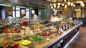 A buffet area with various food items and chefs working in the background.