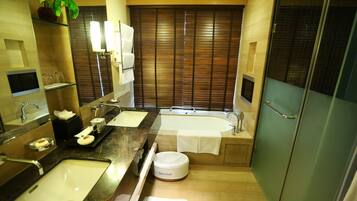 A modern bathroom with a large mirror, dual sinks, a bathtub, and a toilet.