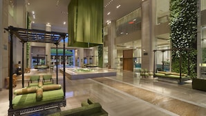 A spacious lobby with a central seating area, a hanging green canopy, and lush vertical greenery on the walls.